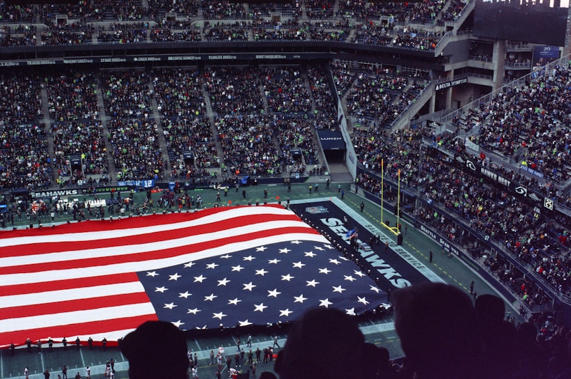 a large american flag is displayed in a stadium