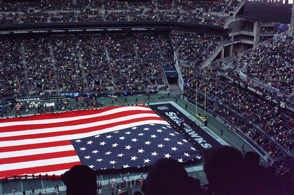 a large american flag is displayed in a stadium