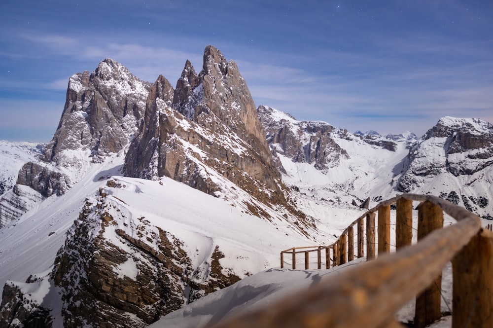 a wooden railing overlooks a snowy mountain range