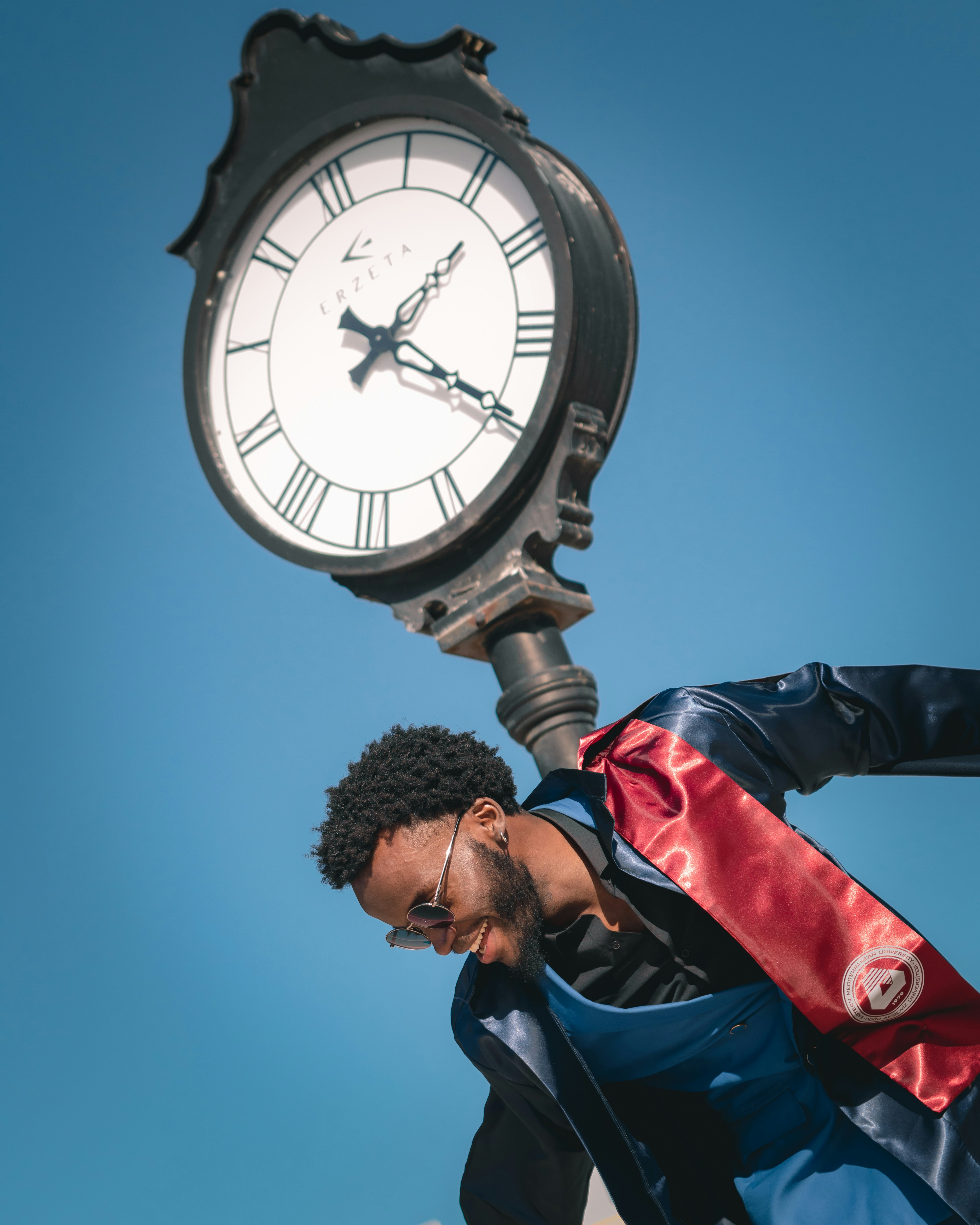 um homem de pé ao lado de um relógio em cima de um poste