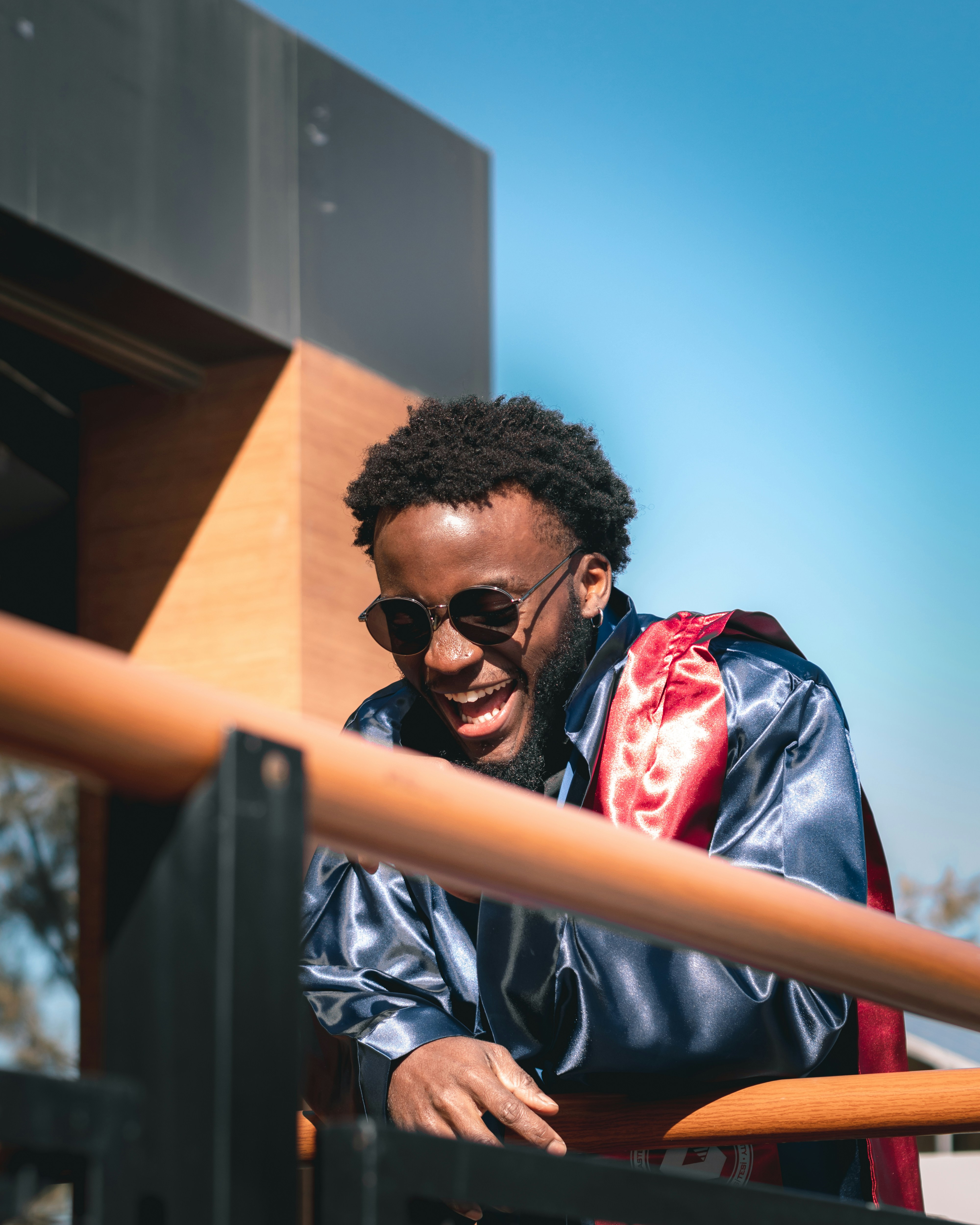 um homem usando óculos escuros e uma jaqueta azul apoiada em um corrimão