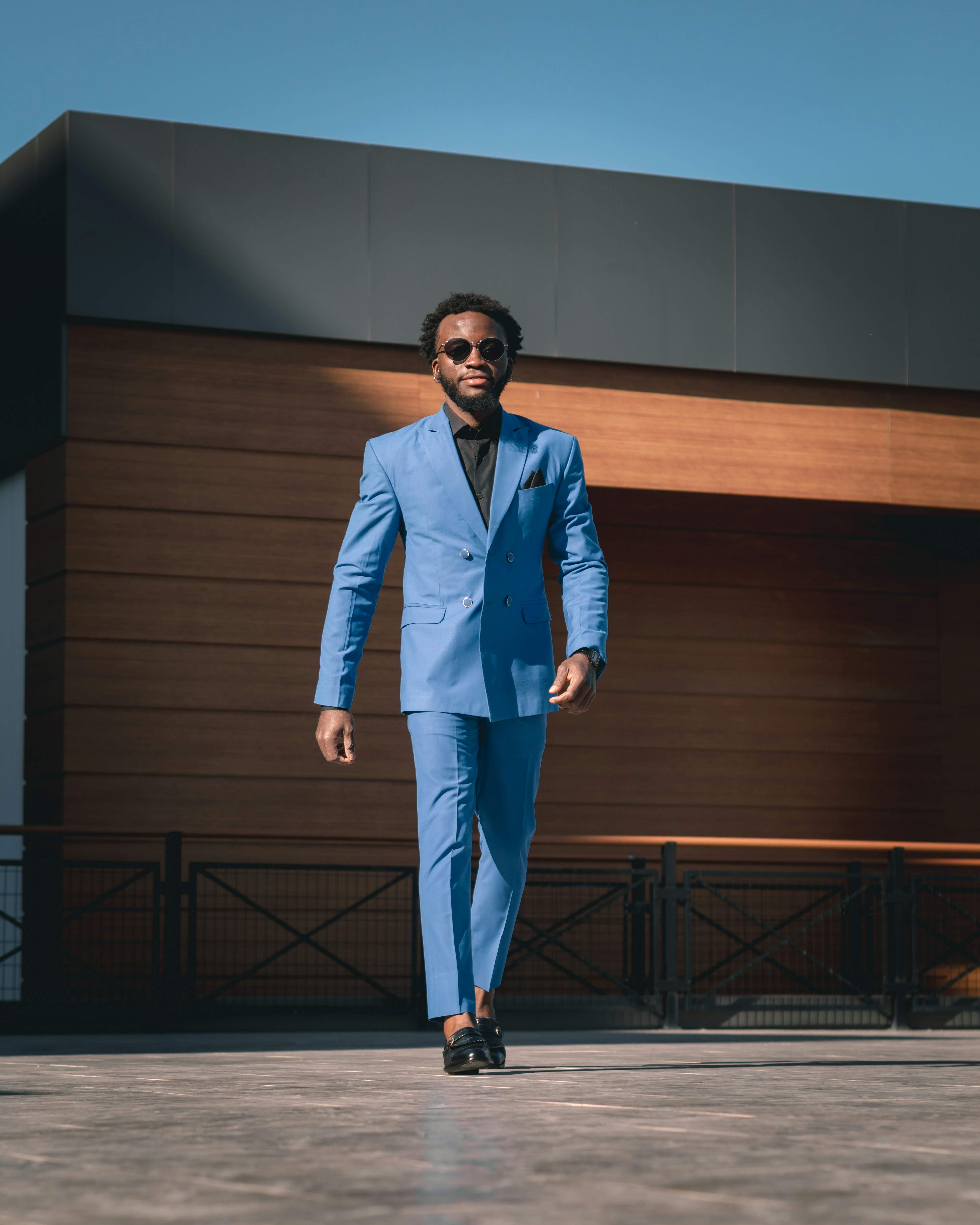 a man in a blue suit walking down a street