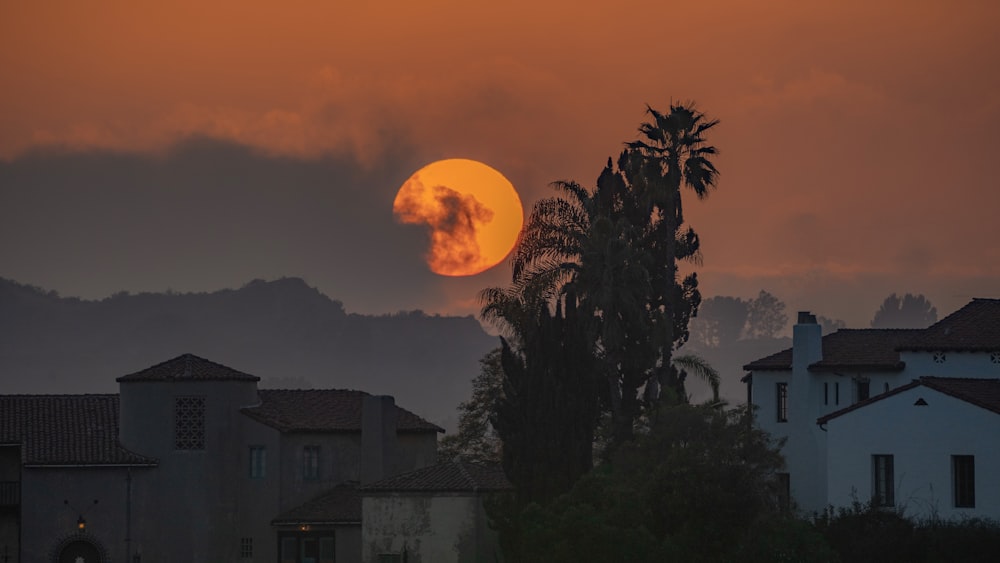 the sun is setting over the mountains behind a house