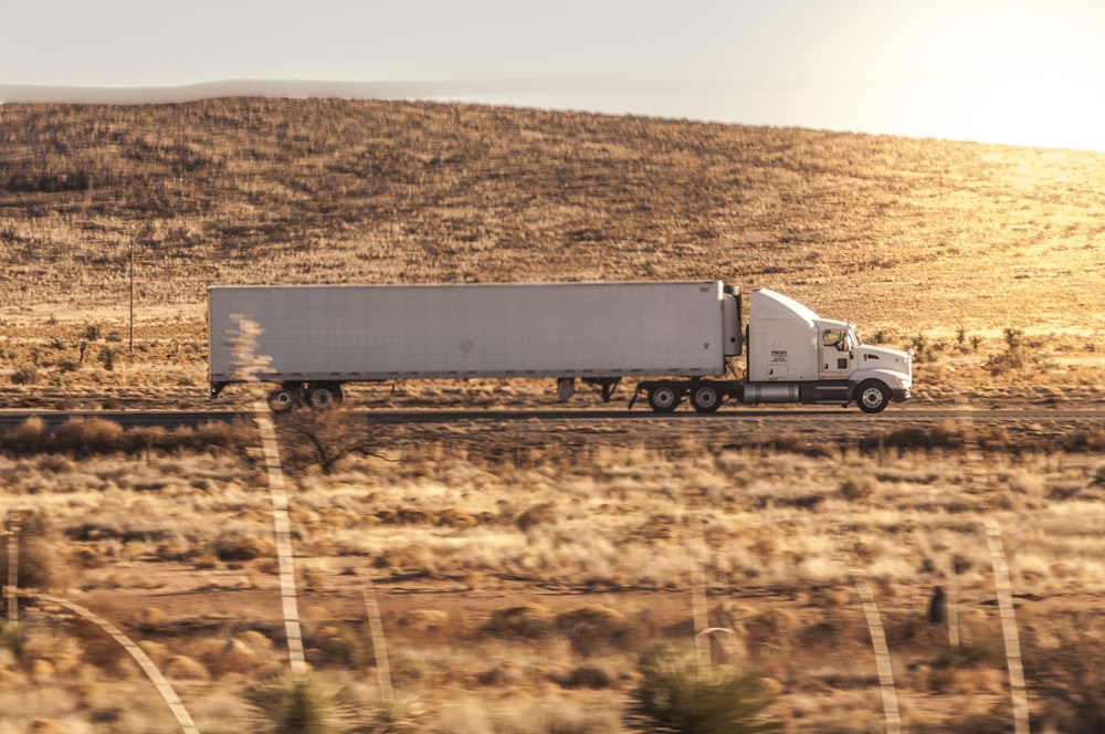 a white semi truck driving down a rural road