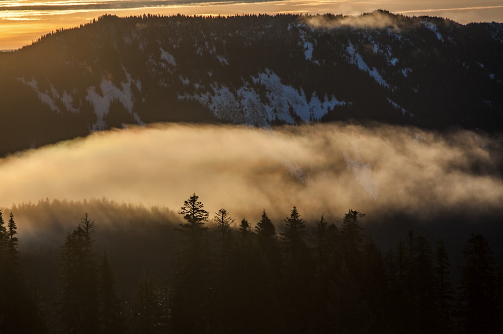 the sun is shining through the clouds in the mountains