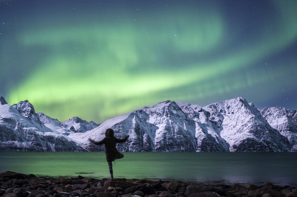 a woman standing on a rocky beach under a green and purple sky