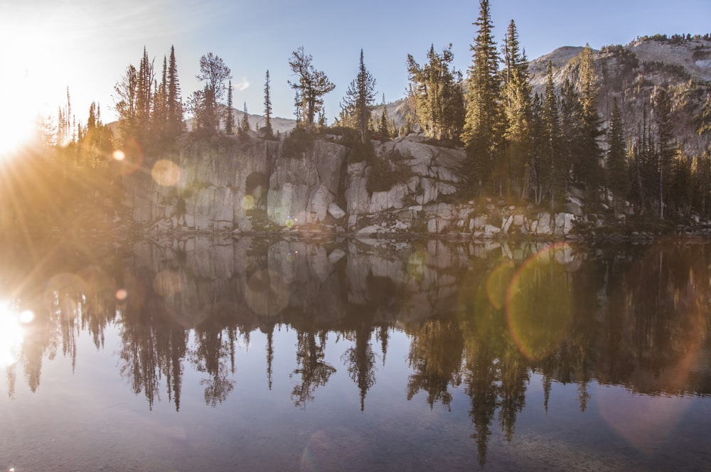 the sun shines on a mountain lake surrounded by trees