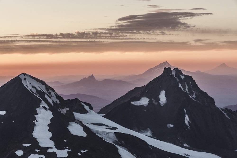 um grupo de montanhas cobertas de neve sob um céu nublado