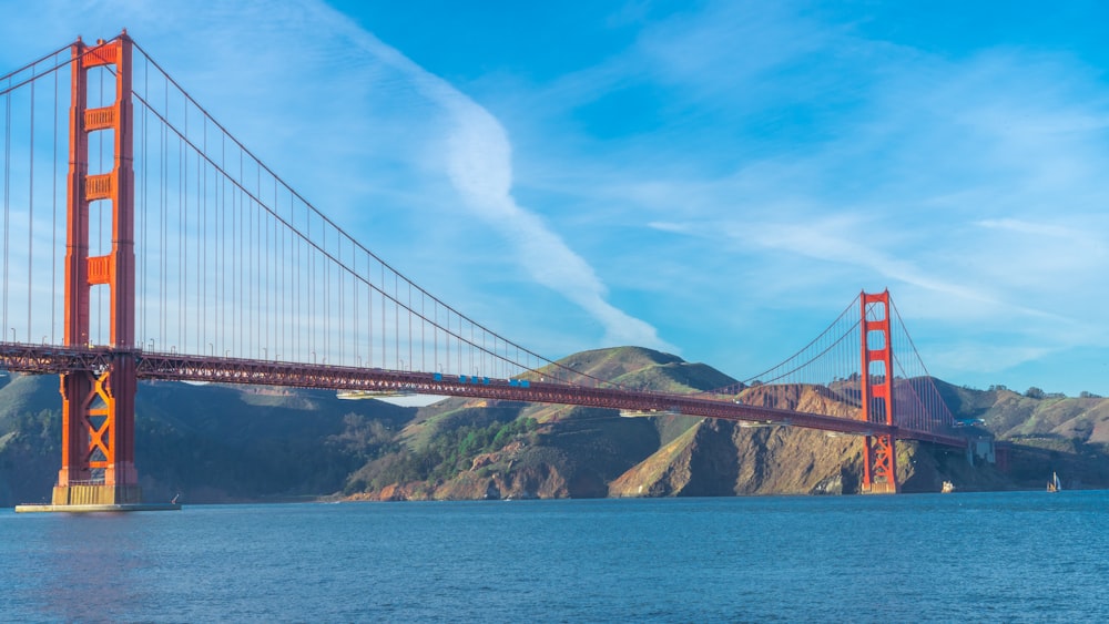 the golden gate bridge over the water with mountains in the background