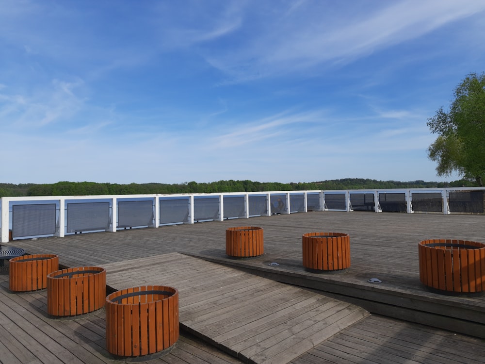 a row of orange trash cans sitting on top of a wooden deck