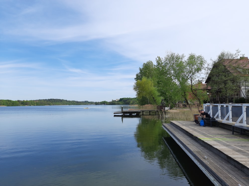 a person sitting on a dock next to a body of water