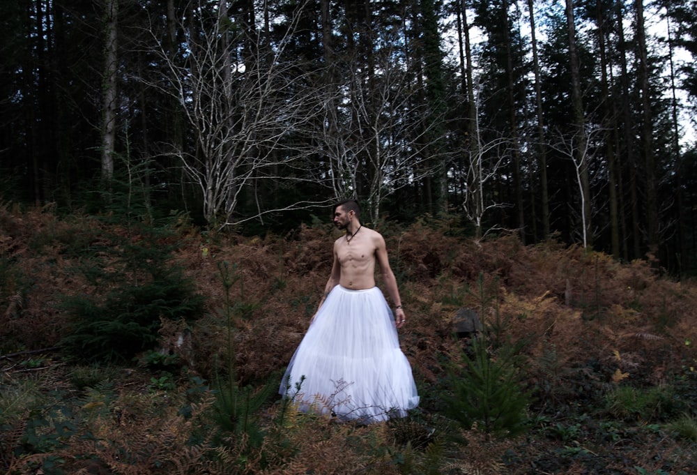 a man in a white dress standing in a forest