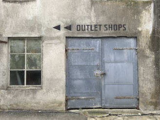 an old building with two blue doors and a sign that says outlet shops