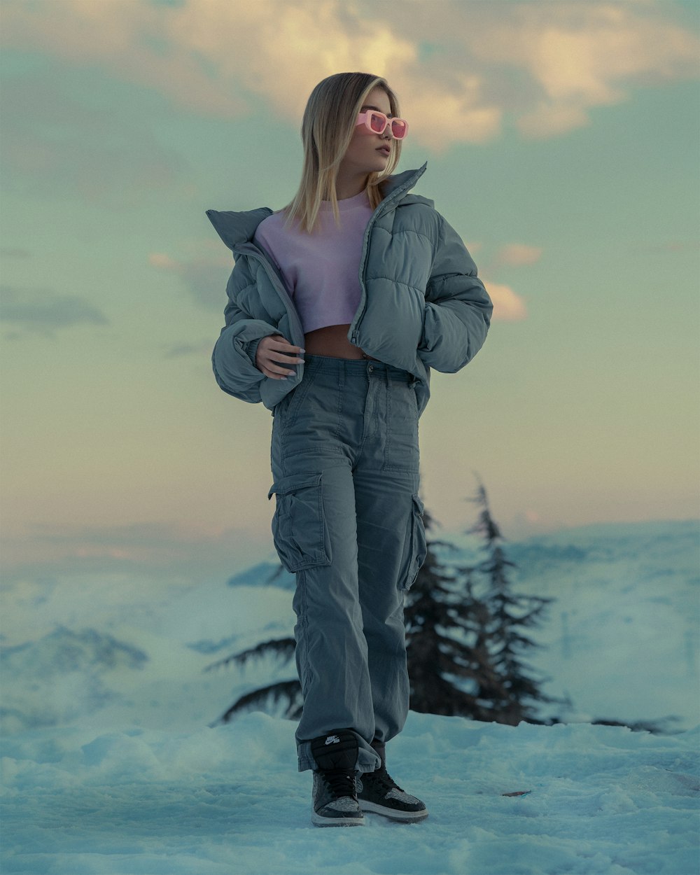 a woman standing in the snow wearing a jacket and pants