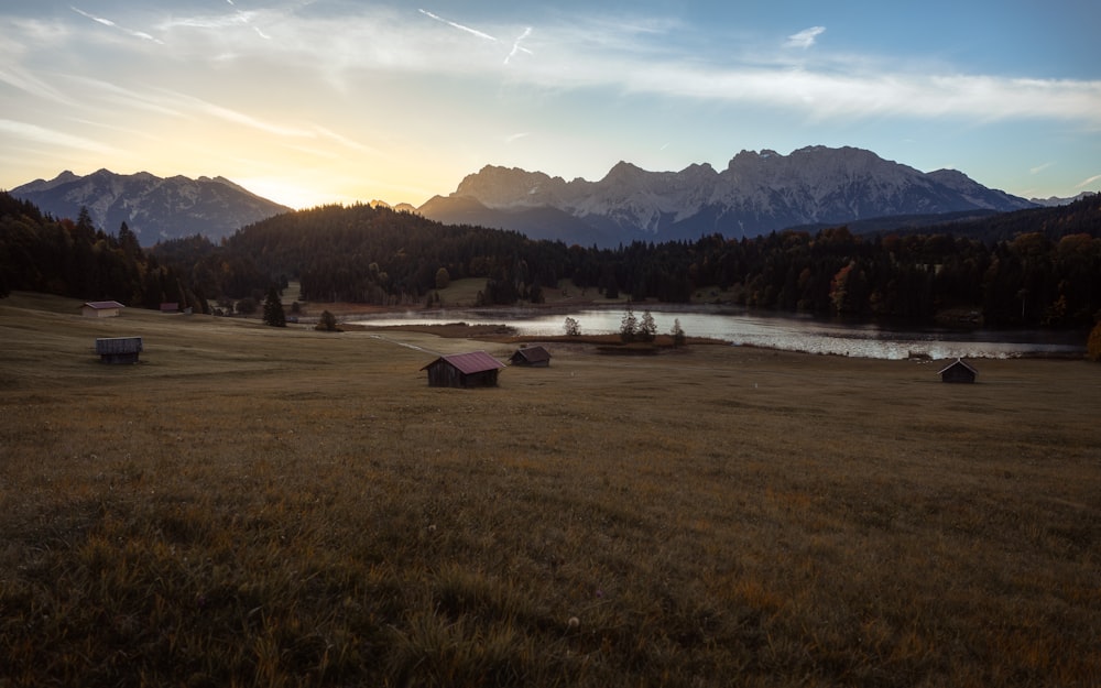 a grassy field with a lake and mountains in the background