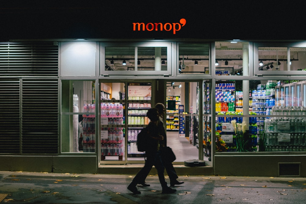 two people walking in front of a store at night