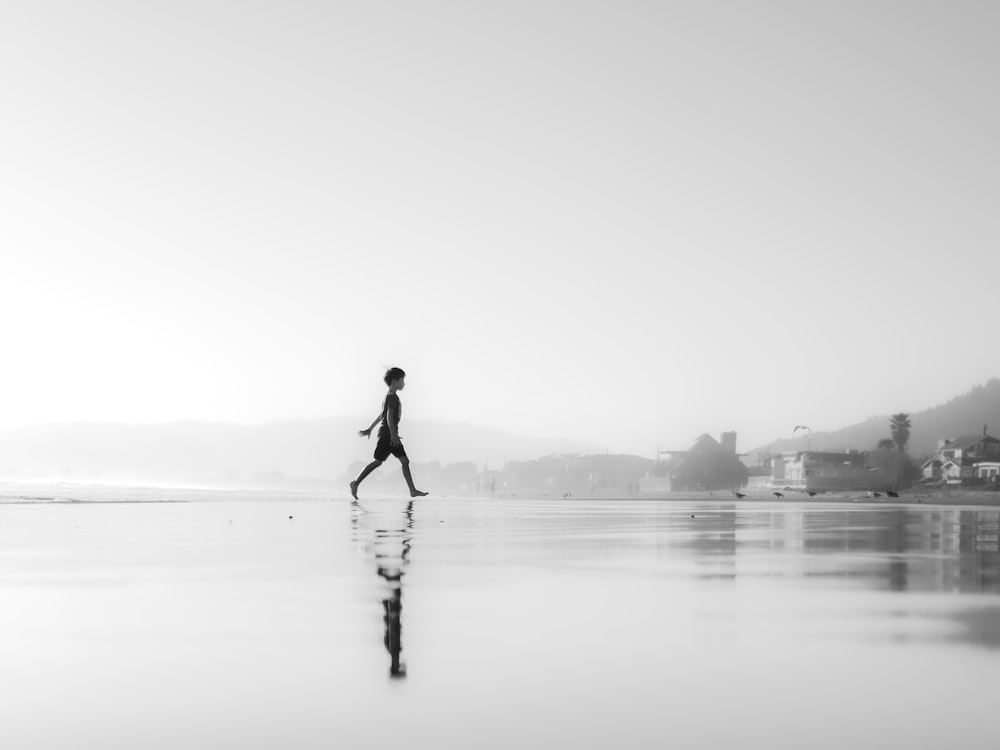 a person walking across a wet beach next to the ocean