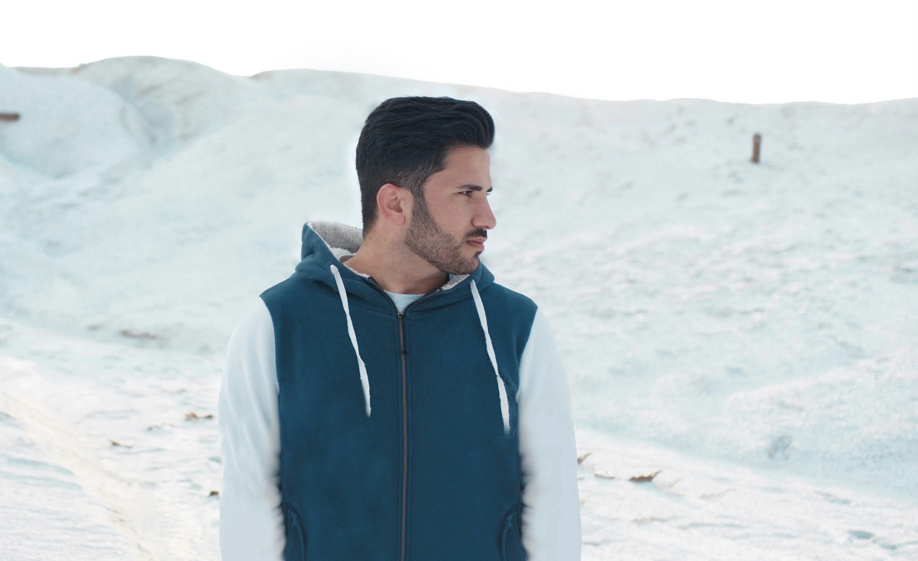 a man standing in the snow wearing a blue and white hoodie