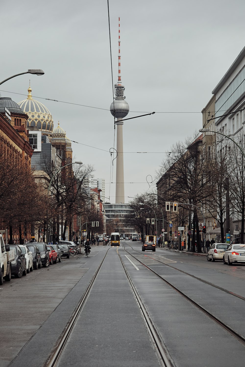 a street with cars parked on both sides and a television tower in the background