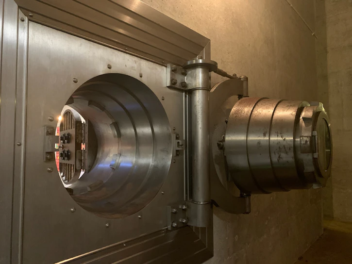 A sturdy, modern security vault door slightly ajar, revealing a glimpse of neatly stacked valuables inside.