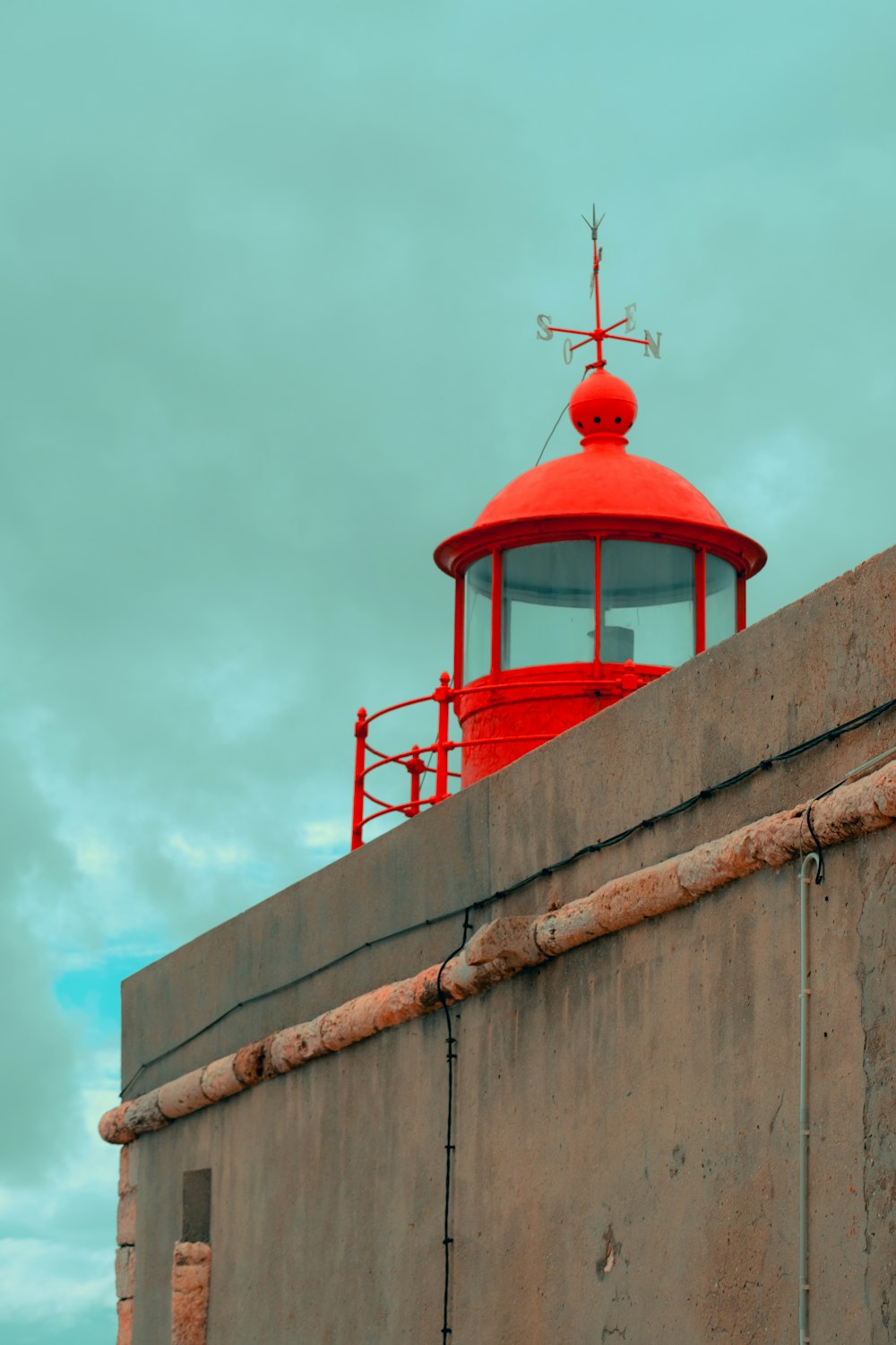a red light house sitting on top of a cement wall