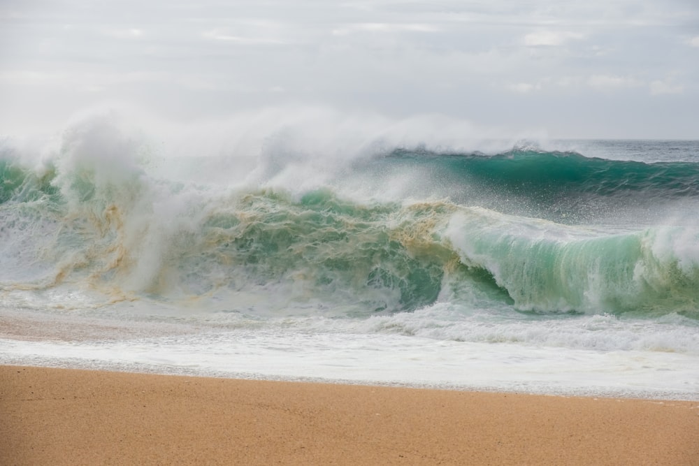 a large wave crashing on a sandy beach