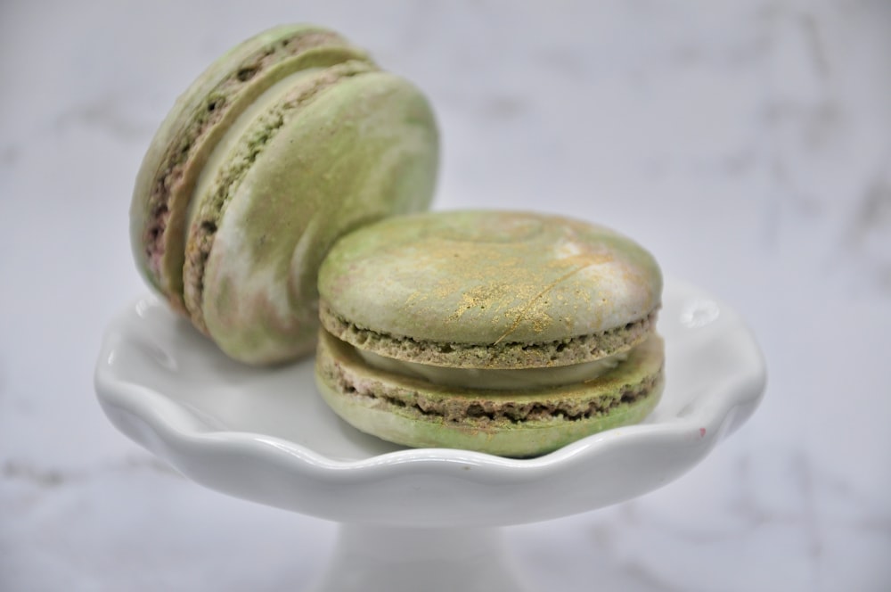 a white plate topped with green macaroons on top of a table