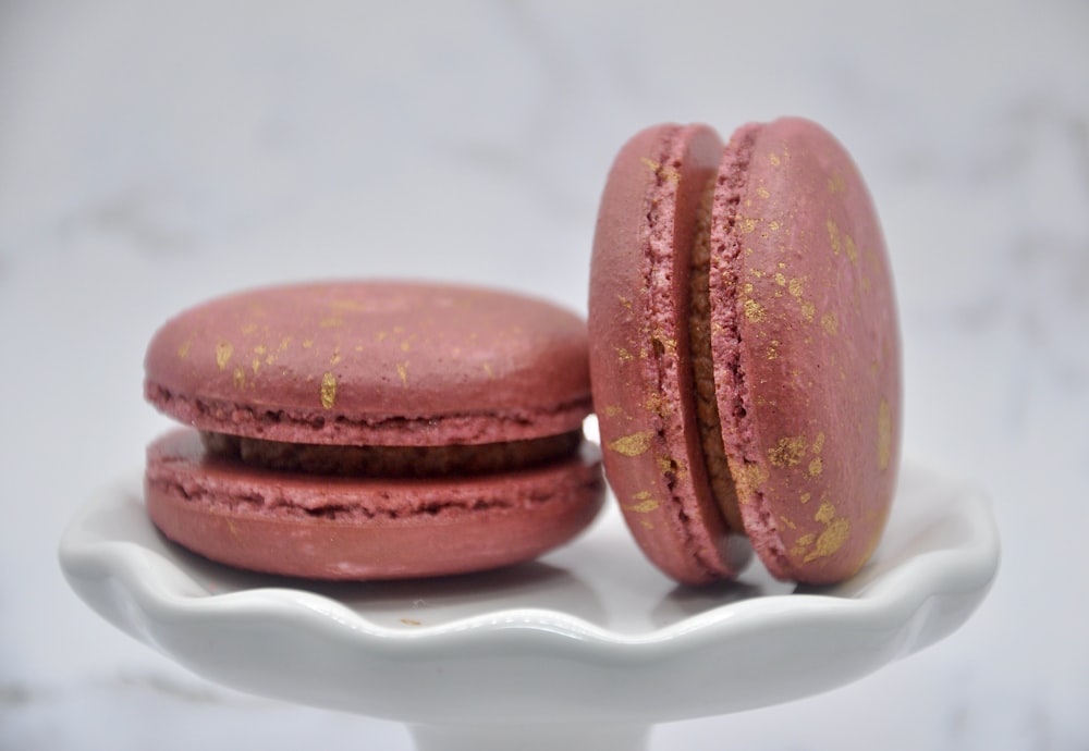 two pink macaroons sitting on a white plate