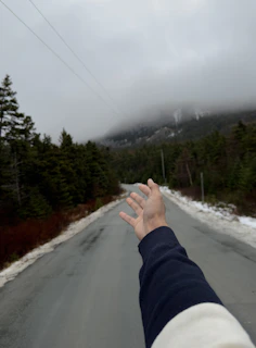 A rugged mountain biker reaching out with a hand to connect, set against a dark, moody forest background.