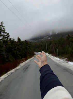 A rugged mountain biker reaching out with a hand to connect, set against a dark, moody forest background.