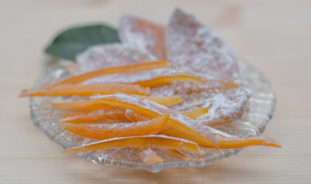 un bol en verre rempli de sucre et d’écorces d’orange