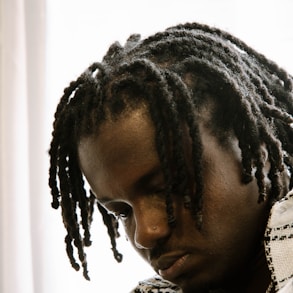 a man with dreadlocks looking down at his cell phone
