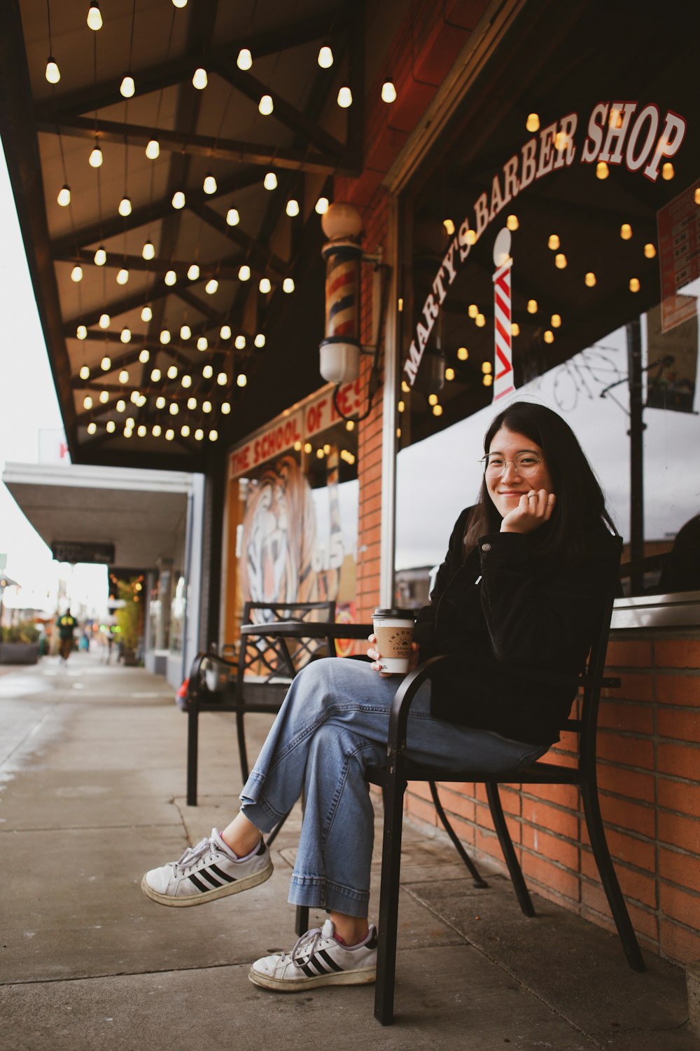 a woman sitting on a chair outside of a barber shop