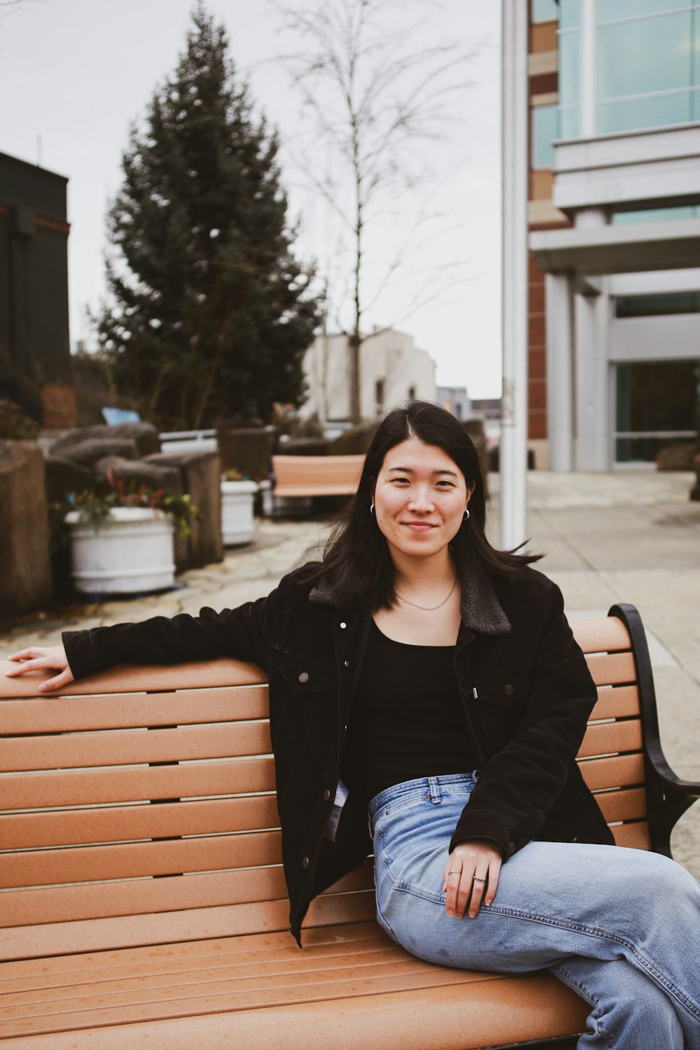 a woman sitting on top of a wooden bench