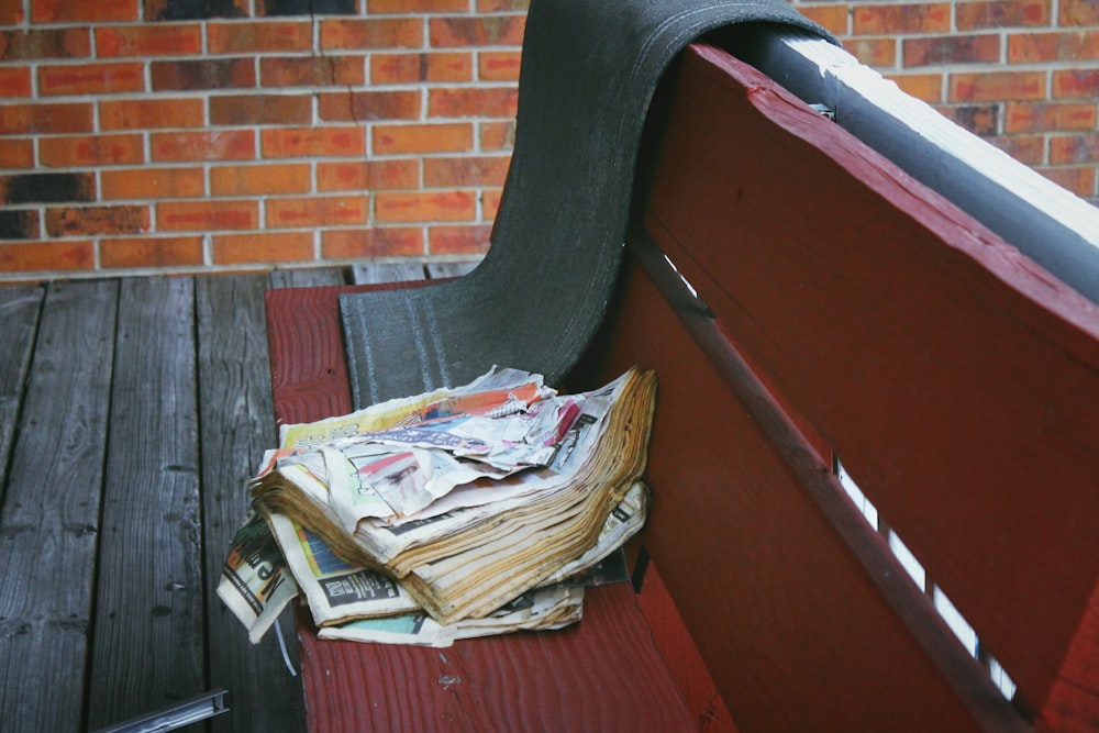 a pile of newspapers sitting on top of a wooden bench