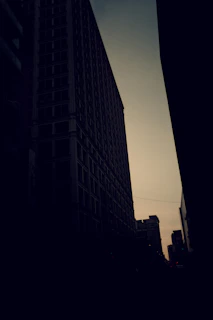 A stark, high-contrast editorial photo of a layered cityscape at dusk, symbolizing complex systems and hidden structures.