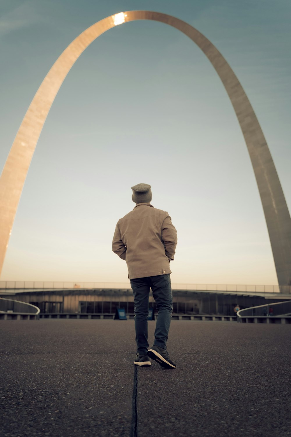 a man riding a skateboard down a street next to a tall arch