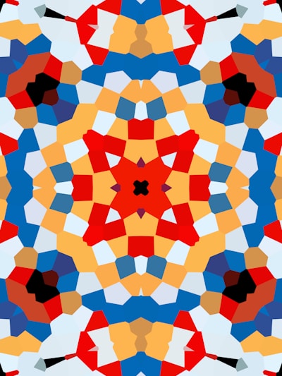 A vibrant, symmetrical kaleidoscope pattern featuring bold geometric shapes in various colors. The design is complex, with intersecting lines and layered segments creating a visually appealing mosaic-like effect.
