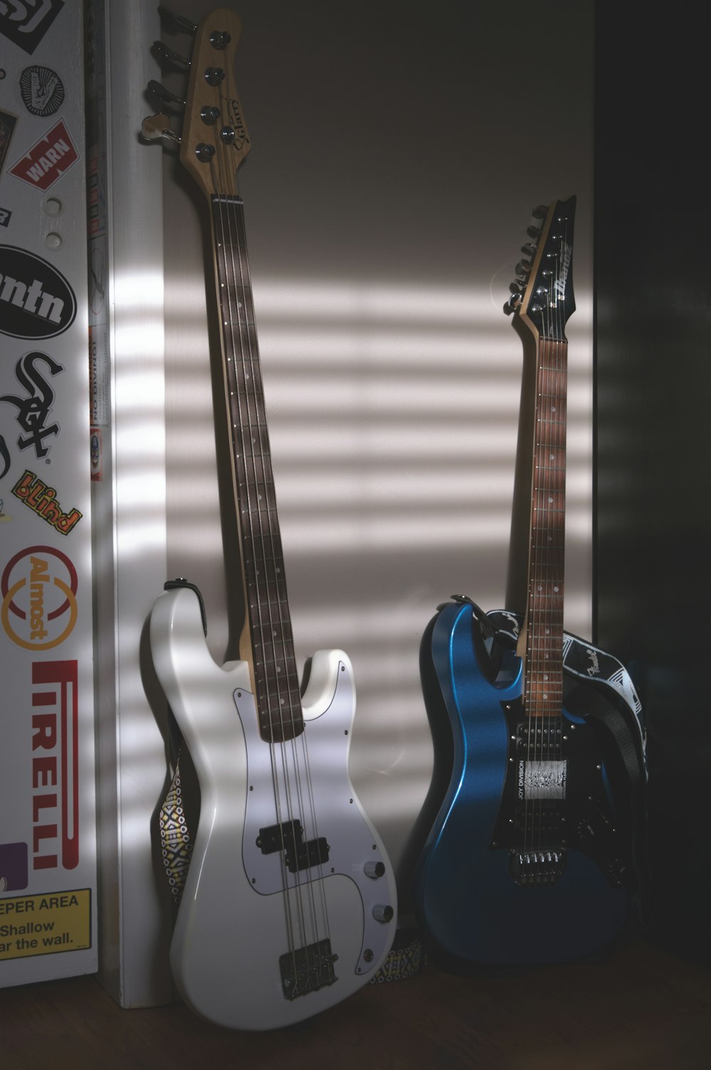 three guitars are lined up against a wall