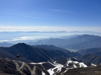 A panoramic view of the Innsbruck mountains with a winding canyon path in the foreground.
