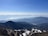 A panoramic view of Swiss cable cars ascending over alpine terrain with distant mountains.