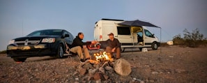 A couple enjoying a campfire next to the campervan under a starry night sky
