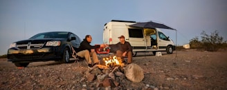 A couple enjoying a campfire next to the campervan under a starry night sky