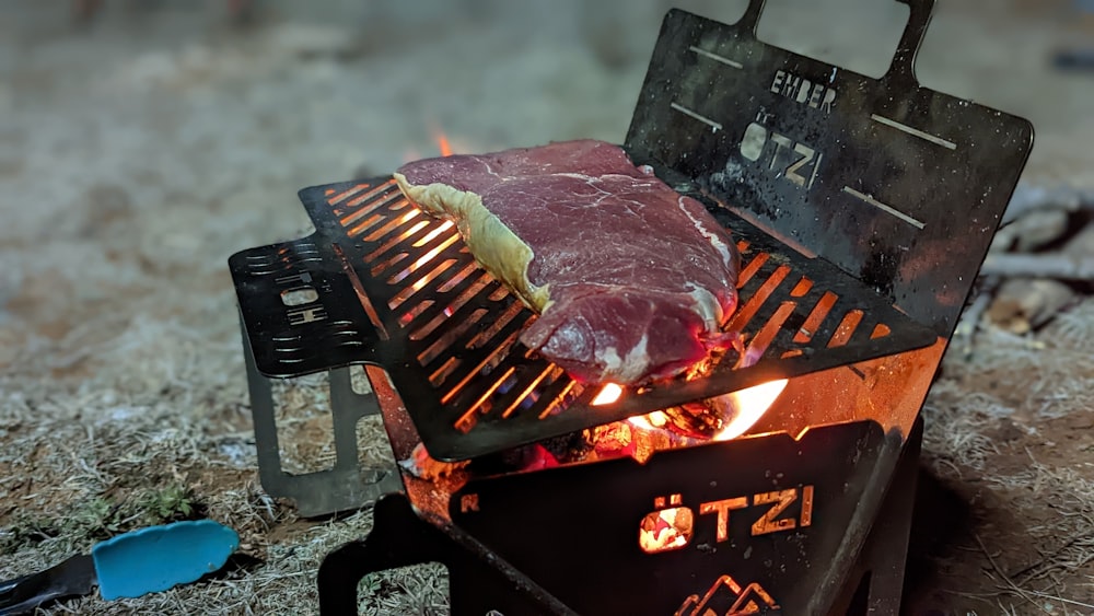 a steak is cooking on a grill on the ground