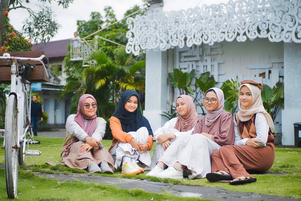 a group of women sitting next to each other on a lush green field