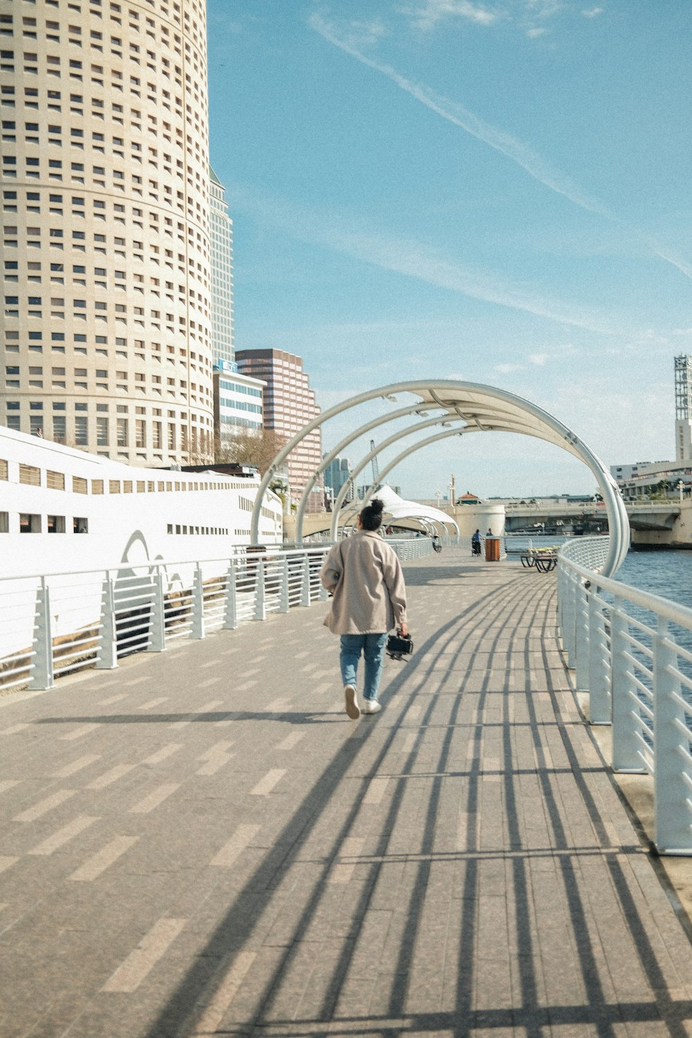 a woman walking down a walkway next to a body of water