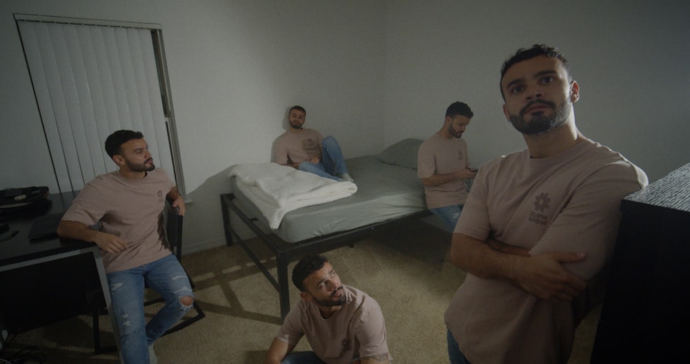 a group of men sitting around a bed in a room