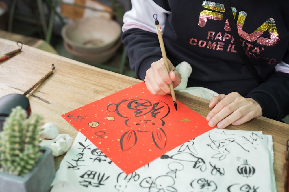 a person sitting at a table with a red piece of paper