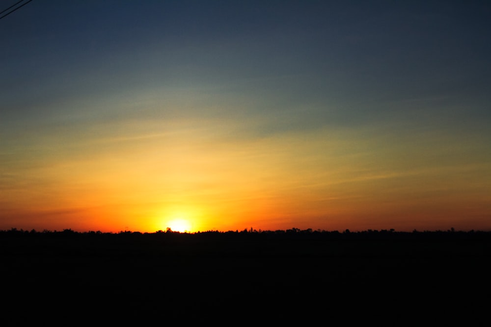 the sun is setting in the sky over a field