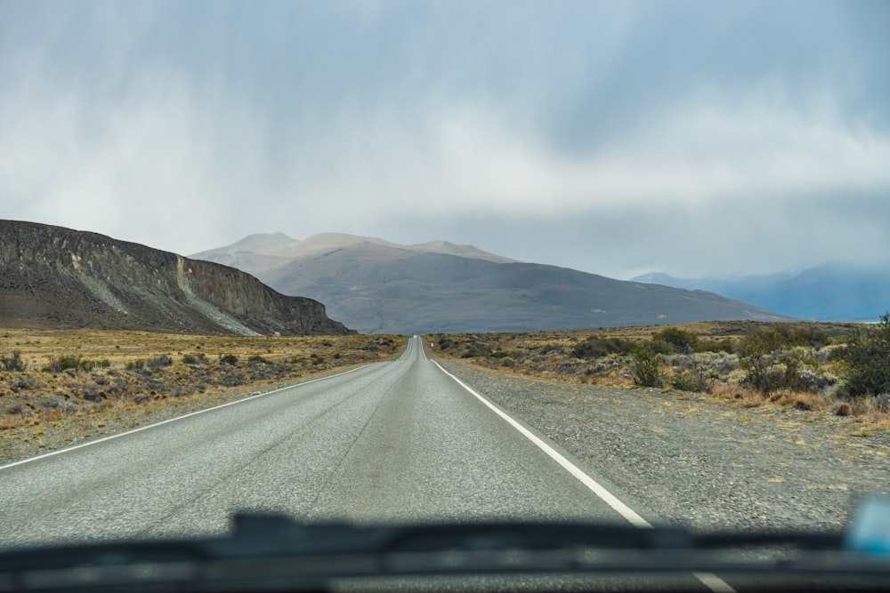 a car driving down a road with mountains in the background